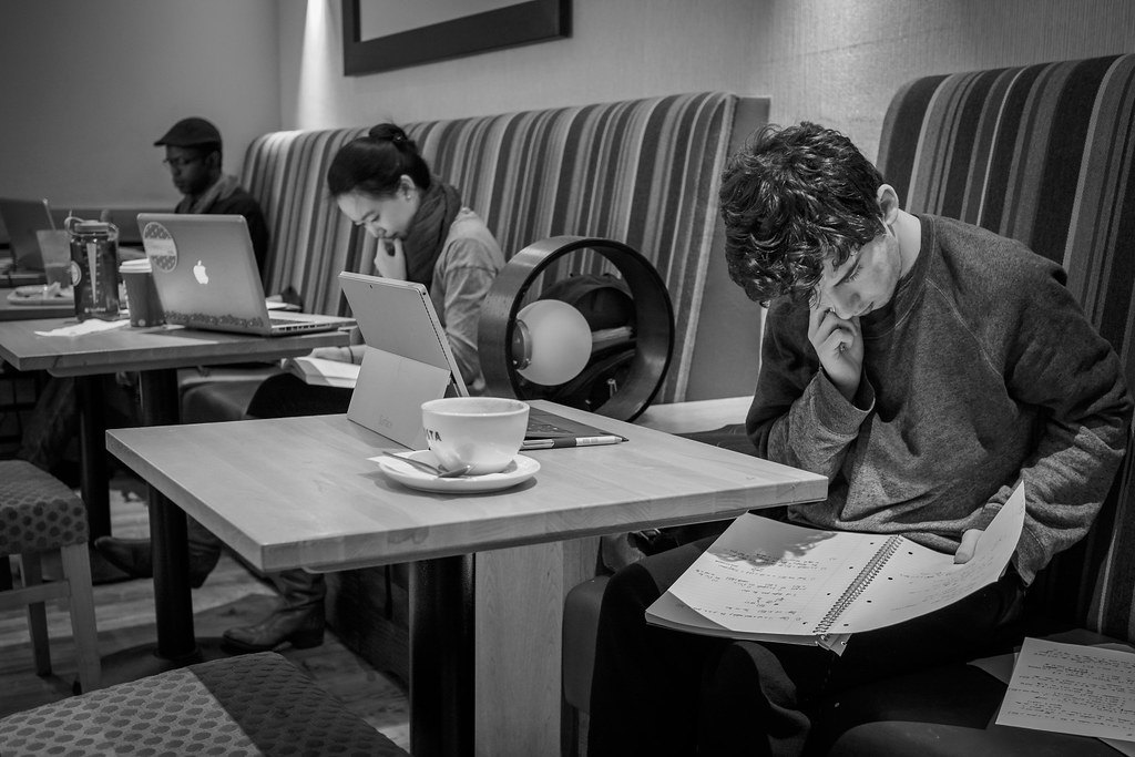 Lycéen en terminale révisant ses cours dans un café avec cahier et boisson chaude